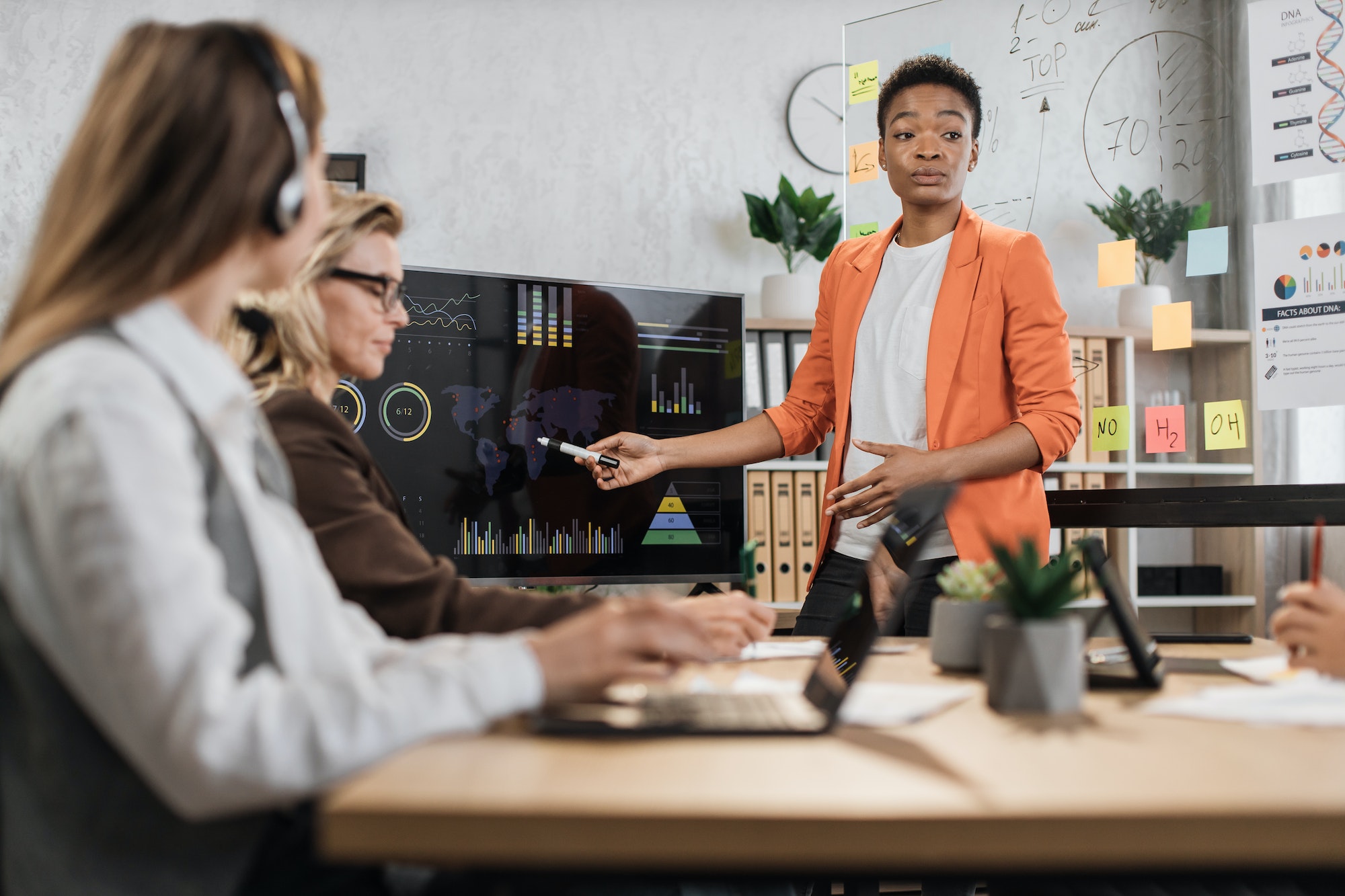 African american woman in orange suit showing financial statistic of enterprise during meeting